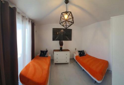 2 letti in una camera da letto con lenzuola arancioni e lampada di Super cool villa in Los Cristianos a Los Cristianos