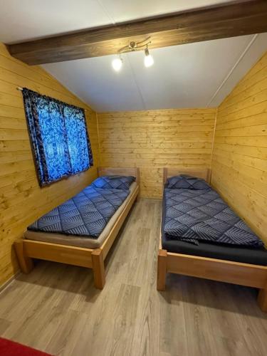 two beds in a room with wooden walls at Domčeky na Ranči in Sučany