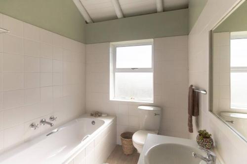 a bathroom with a tub and a toilet and a sink at Oyster Catcher in Cape St Francis