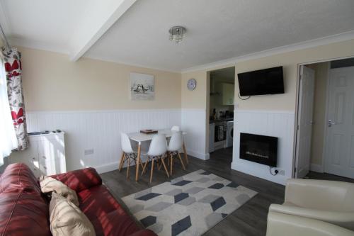 a living room with a couch and a table at Relaxing Chalet on popular California Sands short stroll to beach, nr Norfolk Broads & Great Yarmouth in Scratby