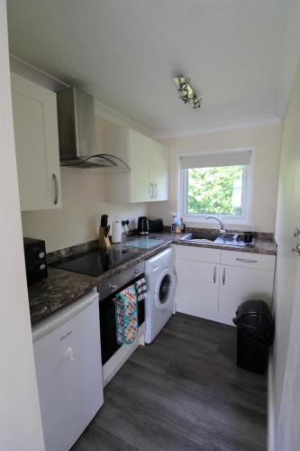 a kitchen with white cabinets and a sink and a dishwasher at Relaxing Chalet on popular California Sands short stroll to beach, nr Norfolk Broads & Great Yarmouth in Scratby