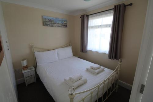 a bedroom with a bed with two towels on it at Relaxing Chalet on popular California Sands short stroll to beach, nr Norfolk Broads & Great Yarmouth in Scratby