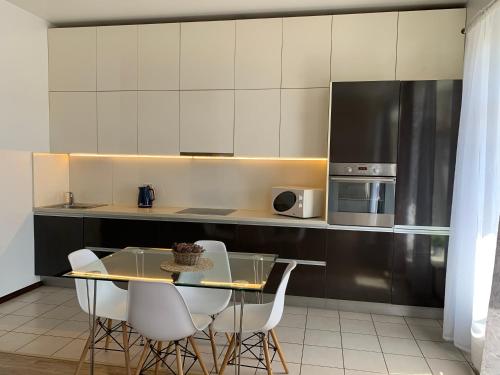 a kitchen with a glass table and white cabinets at Near Station Apartment in Vilnius