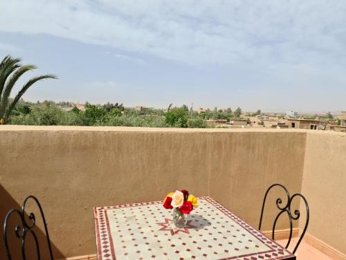 une table avec un vase de fleurs sur une table dans l'établissement Kasbah Ait ben Damiette, à Skoura