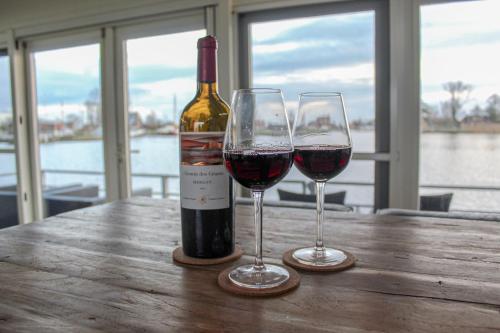 two glasses of red wine sitting on a wooden table at Luxe woonboot unieke locatie Friesland Âlde Feanen in De Veenhoop