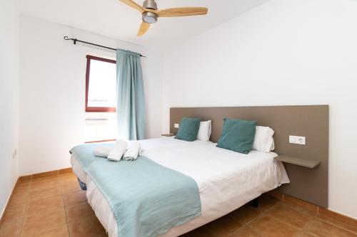 a bedroom with a large white bed with blue pillows at UpTown Urban Apartments in Corralejo