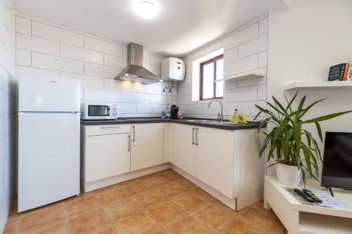 a kitchen with white cabinets and a refrigerator at UpTown Urban Apartments in Corralejo