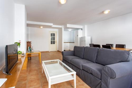 a living room with a blue couch and a table at UpTown Urban Apartments in Corralejo