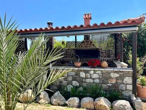 a patio with a stone fireplace in a yard at Elli's apartments in Antimácheia