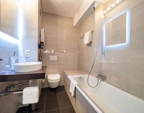 a bathroom with a tub and a toilet and a sink at Hotel Best Western City Centre in Brussels