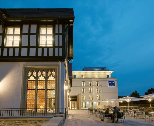 a building with tables and chairs in front of a building at Dorint Hotel Frankfurt/Oberursel in Oberursel