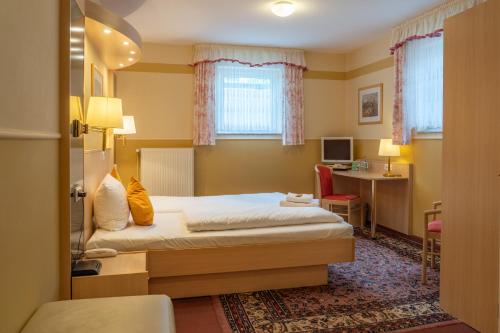 a hotel room with a bed and a desk at Parkhotel Neustadt Garni in Neustadt