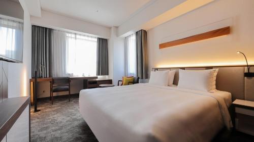 a hotel room with a large white bed and a desk at ANA Holiday Inn Sendai by IHG in Sendai