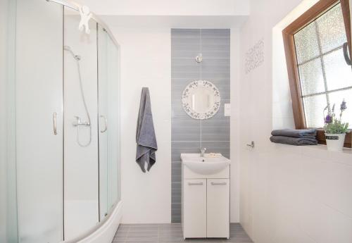 a white bathroom with a shower and a sink at Kwatery Prywatne Dzika Roza in Darłowo