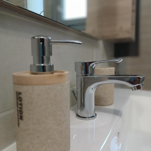 a bathroom sink with a soap dispenser next to a faucet at Anesi Vista Apartment in Vasiliki