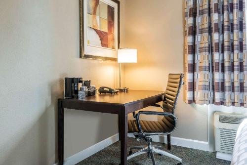 a desk with a chair and a lamp at Clarion Inn Belle Vernon in Belle Vernon