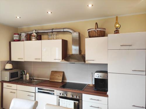 a kitchen with white cabinets and a stove top oven at Apartament GórnyŚląsk blisko jeziora - 120qm - 3 sypialnie z parkingiem i klimatyzacją - Flat UpperSilesia with Parking & air conditioning - Ferienwohnung OberSchlesien mit 3 Schlafzimmern inklusive Parkplatz und Klima - Nähe Badesee und Sandstrand in Niewiesze