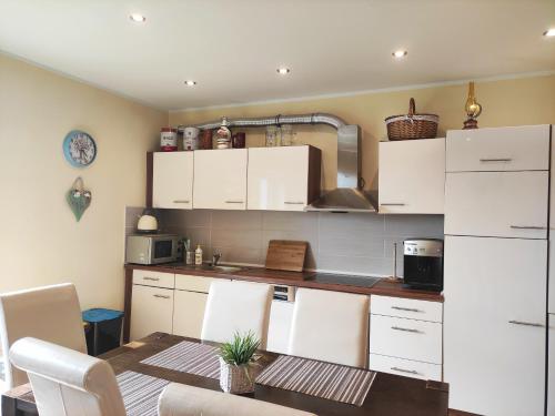 a kitchen with white cabinets and a table with chairs at Apartament GórnyŚląsk blisko jeziora - 120qm - 3 sypialnie z parkingiem i klimatyzacją - Flat UpperSilesia with Parking & air conditioning - Ferienwohnung OberSchlesien mit 3 Schlafzimmern inklusive Parkplatz und Klima - Nähe Badesee und Sandstrand in Niewiesze