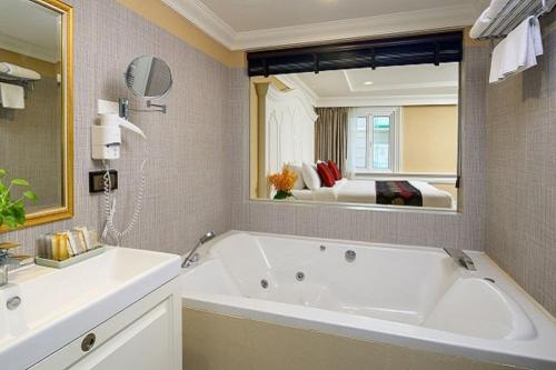 Kingston Suites Bangkok في بانكوك: حمام مع حوض كبير ومرآة كبيرة