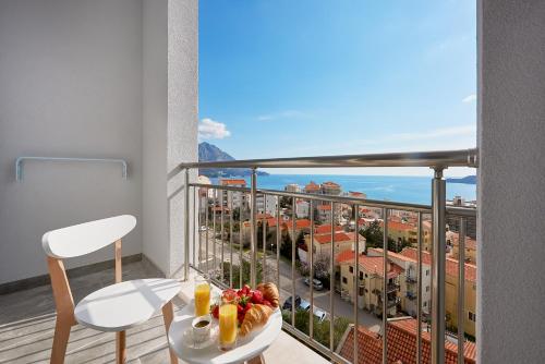 a room with a balcony with a view of the ocean at Garni Hotel Larimar in Budva