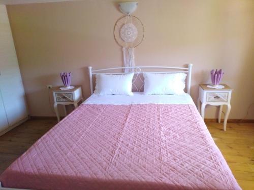 een slaapkamer met een roze bed en 2 tafels bij Arhontiko Katerina Spili in Árdhaktos