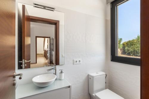 uma casa de banho branca com um lavatório e um espelho em Colonies em Ses Salines