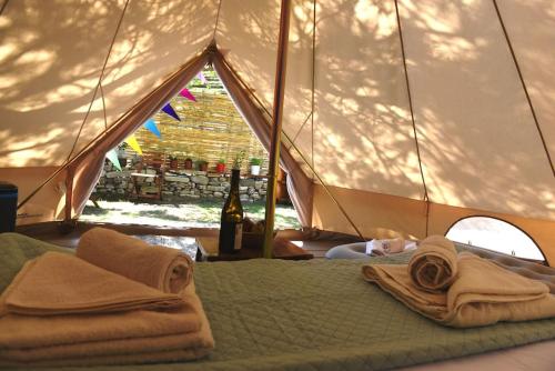 Una cama en una tienda con toallas y una botella de vino en Happy Glamping, en Kalamaki
