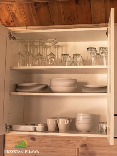 a kitchen cabinet filled with dishes and glass jars at Przystań Piława in Borne Sulinowo