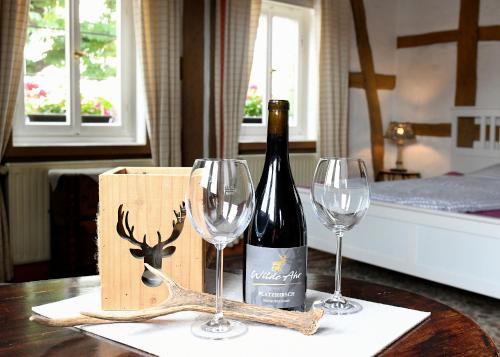 eine Flasche Wein und zwei Weingläser auf dem Tisch in der Unterkunft Burgmannenhaus in Steinau an der Straße