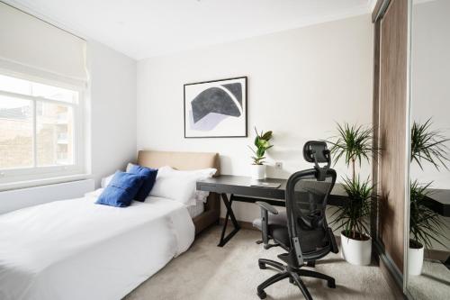 um quarto com uma secretária, uma cama e uma cadeira em Cosy Two Bedroom Apartment in Holborn em Londres