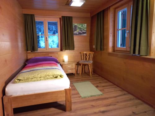 um pequeno quarto com uma cama e uma cadeira em Ferienwohnung Stelzis em Wald am Arlberg