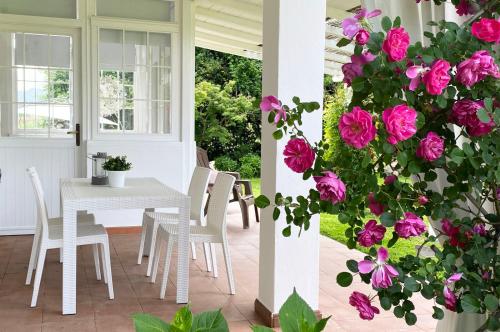 uma mesa e cadeiras num alpendre com rosas rosas em PIETRASANTA-VERSILIA - Delizioso Cottage al mare em Pietrasanta