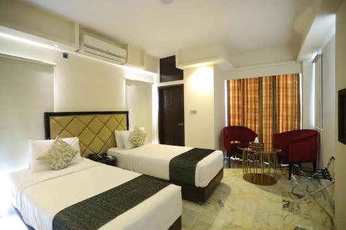 a hotel room with two beds and a table at The Elite Residence Dhaka in Dhaka
