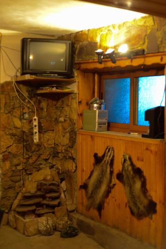 a living room with a stone fireplace and a tv at Topuzovi Guest House in Dobrinishte