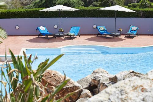 a swimming pool with blue chairs and umbrellas at Villa Dennis in Vrahati