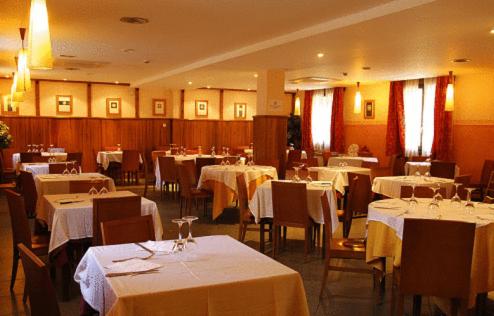 une salle à manger avec des tables, des chaises et un tissu de table blanc dans l'établissement Hotel Pirineos, à Castejón de Sos