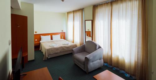 a hotel room with a bed and a chair at Dionis Hotel in Varna City