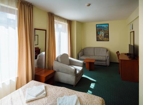 a hotel room with a couch and a chair at Dionis Hotel in Varna City