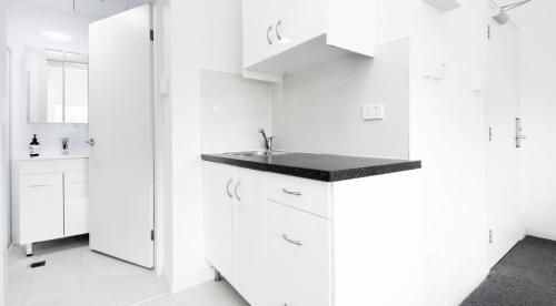 a white kitchen with white cabinets and a sink at Excelsior Apartments at Glebe in Sydney