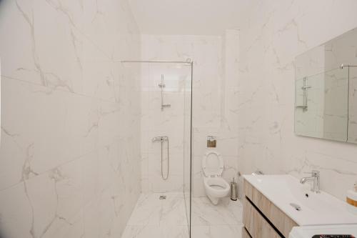 a white bathroom with a shower and a toilet at Trsteno Beach Apartments in Budva