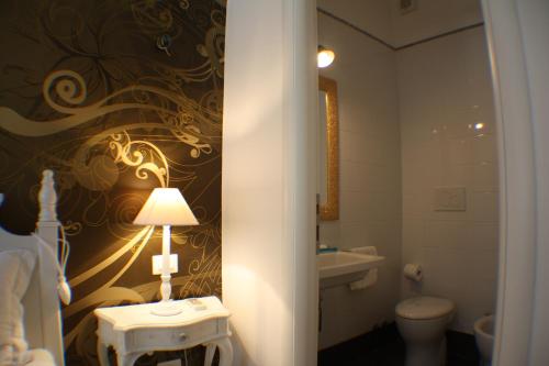 a bathroom with a toilet and a table with a lamp at Conny's Home in Rome