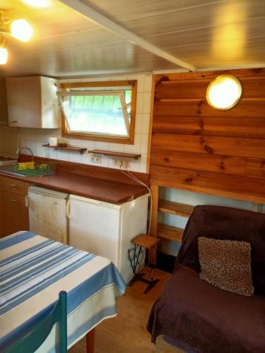 a kitchen with a table and a couch in a room at le bateau sur lac privé de 2 hectares poissonneux au milieu des bois in Florennes