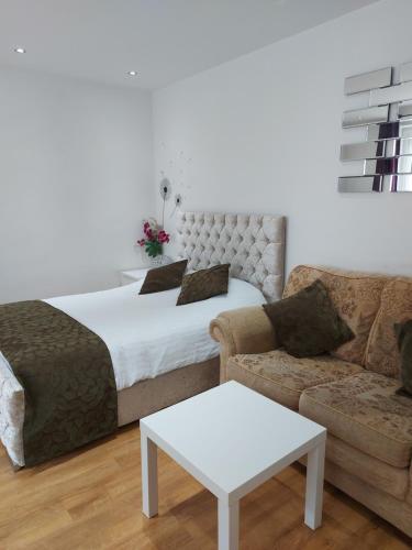 a bedroom with a bed and a couch at Lux Apartment in Gatwick in Crawley