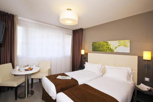 una camera d'albergo con due letti e un tavolo di Séjours & Affaires Montreuil Saint Mandé a Montreuil