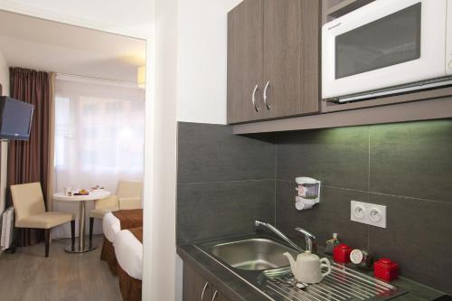 a kitchen with a sink and a microwave at Séjours & Affaires Montreuil Saint Mandé in Montreuil