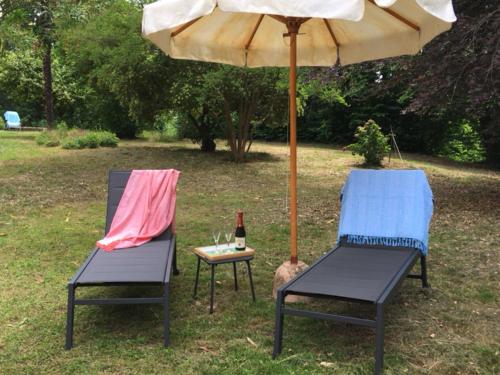 two chairs and an umbrella and a table with a bottle of wine at Villa Bacchus in Cortanze