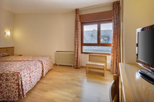 a hotel room with a bed and a tv and a window at Hotel Nievesol in Formigal