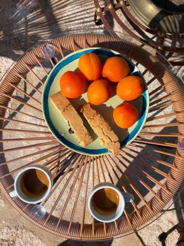 a plate of oranges on a table with two cups of coffee at La Mia Lamia in Cisternino