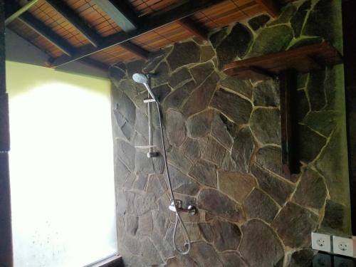 a stone shower in a bathroom with a stone wall at Pier26 Bali Homestay in Nusa Dua