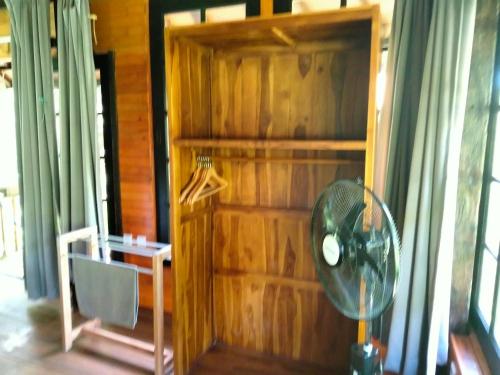 a room with a fan and a wooden wall at Pier26 Bali Homestay in Nusa Dua
